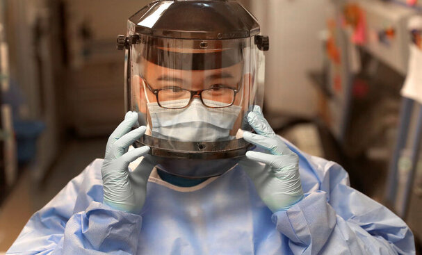 Jinqing Liu, a research technician, adjusts his mask in the sealed-off lab at the Ragon Institute of MGH, MIT, and Harvard.<br/>